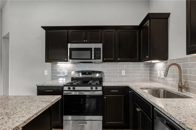 a kitchen with stainless steel appliances granite countertop a stove microwave and sink