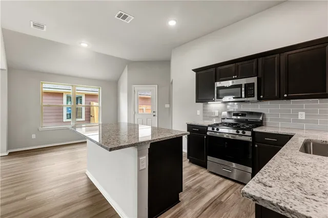 a kitchen with granite countertop wooden cabinets and black stainless steel appliances