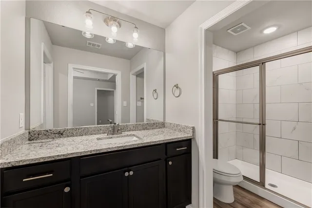 a bathroom with a granite countertop sink toilet and shower
