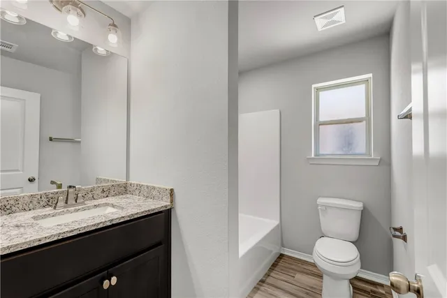 a bathroom with a granite countertop toilet sink and mirror