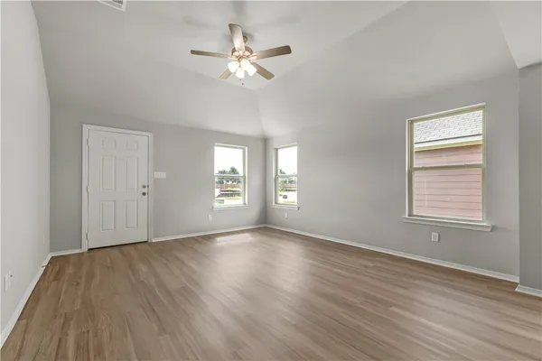 a view of an empty room with a window and wooden floor