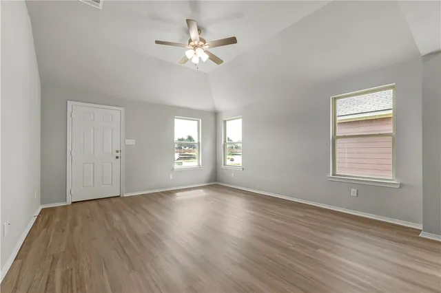 a view of an empty room with a window and wooden floor