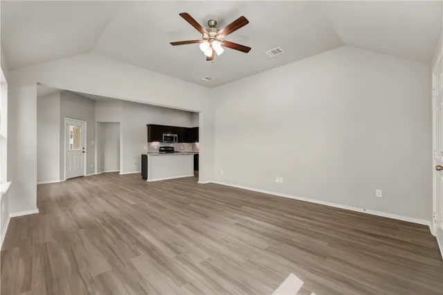 a view of empty room with wooden floor and ceiling fan