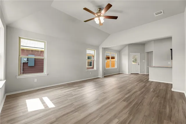 a view of an empty room with window and wooden floor