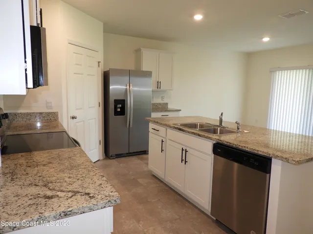 a kitchen with stainless steel appliances granite countertop a sink and a refrigerator