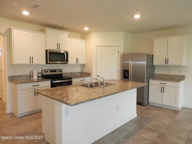 a kitchen with stainless steel appliances granite countertop a refrigerator a stove a sink a stove a oven with white cabinets and wooden floor