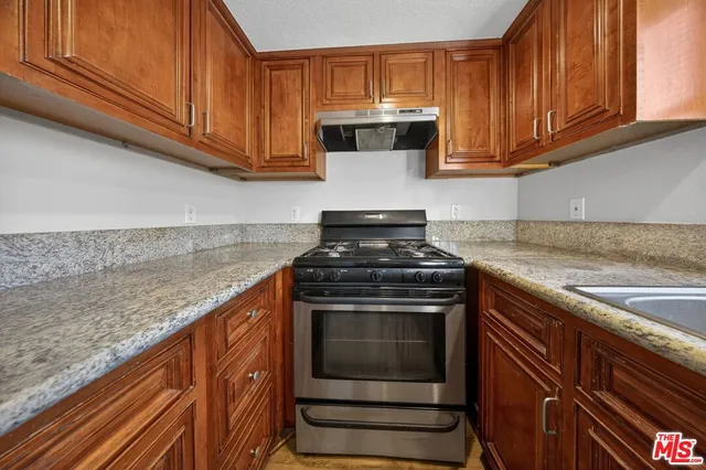 a kitchen with granite countertop wood cabinets and stainless steel appliances