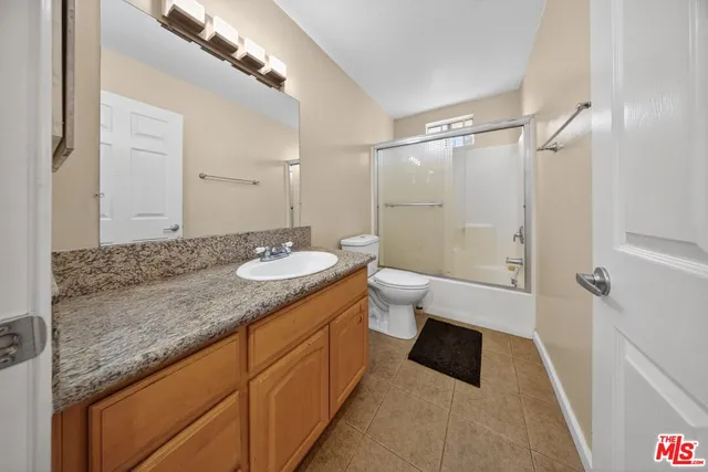a bathroom with a granite countertop sink a toilet a mirror and shower