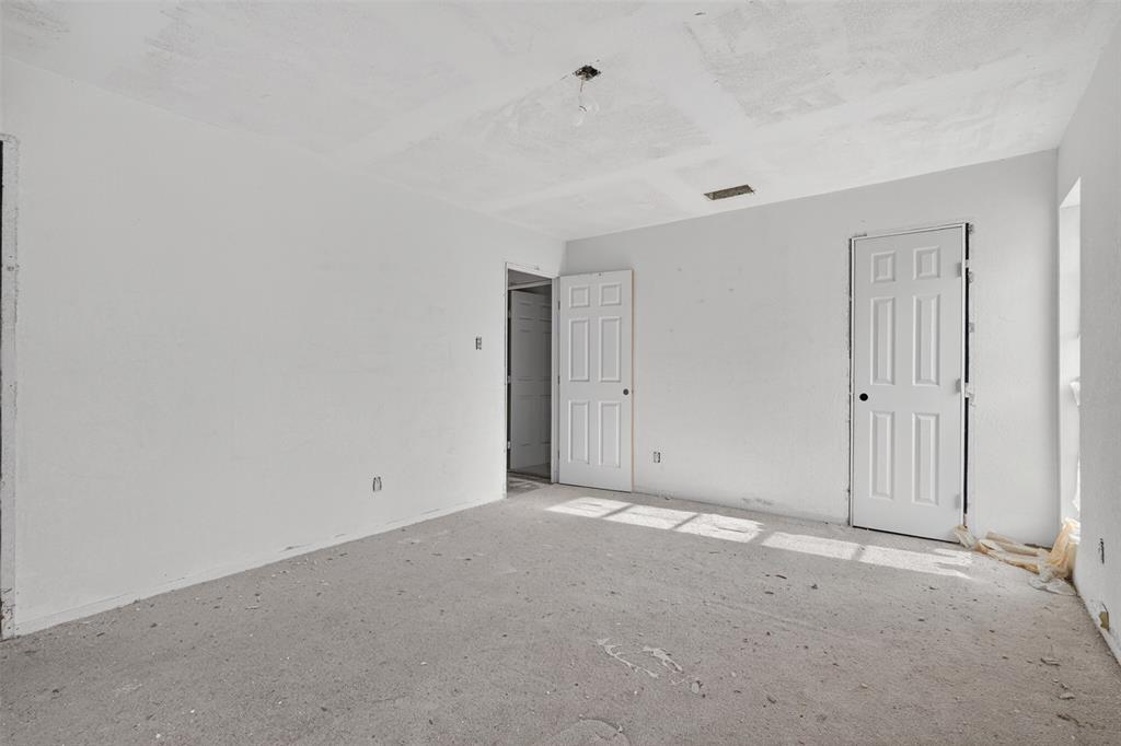 1212 Manning Road Benbrook, TX 76126 - Photo 13 of 20 Room featuring a concrete subfloor, white walls, two white paneled doors, and an exposed ceiling light fixture
