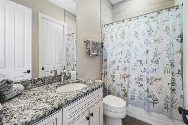 a bathroom with a granite countertop sink a toilet and a mirror