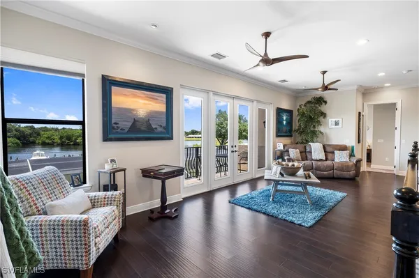 a living room with furniture floor to ceiling window hardwood floor and a flat screen tv