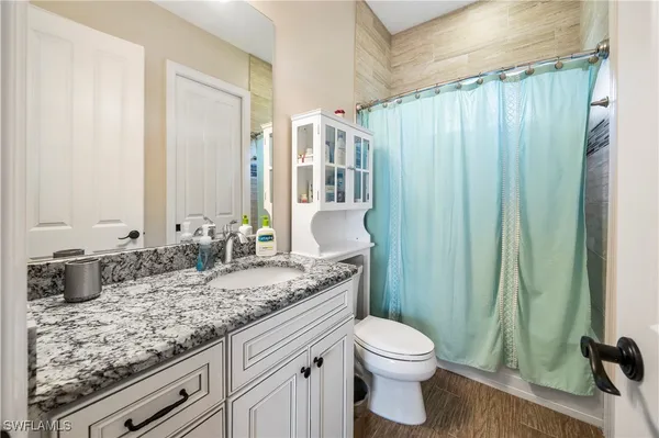 a bathroom with a granite countertop sink a toilet and shower