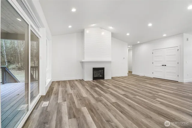 a view of empty room with wooden floor and fireplace