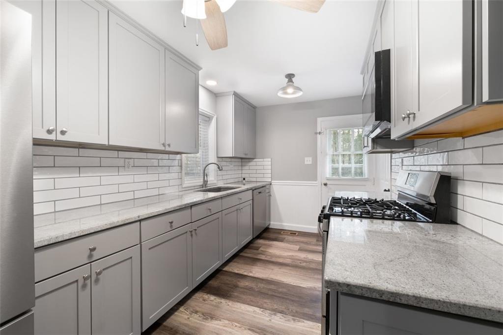 111 Poplar Street Fairburn, GA 30213 - Photo 21 of 32 a kitchen with granite countertop a sink a stove and cabinets