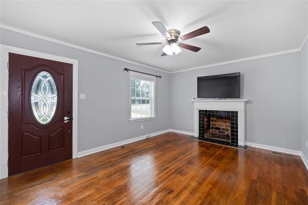 111 Poplar Street Fairburn, GA 30213 - Photo 8 of 32 an empty room with wooden floor a fireplace and a window