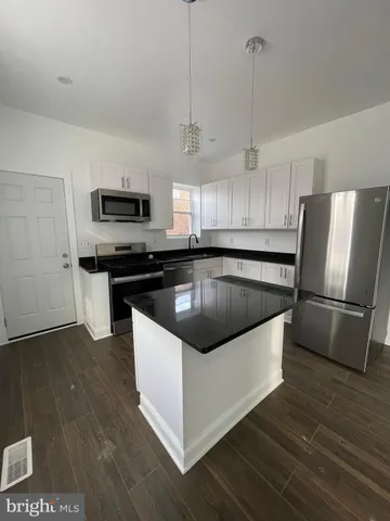 a kitchen with kitchen island a counter top space a sink and stainless steel appliances