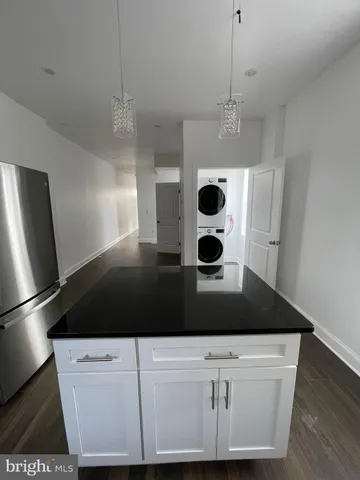 a close view of kitchen island with granite countertop a refrigerator a stove a microwave a counter space and wooden floor