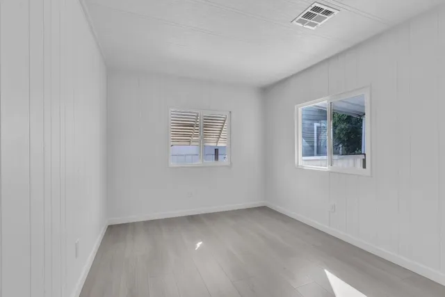 a view of an empty room with window and wooden floor