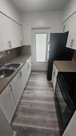 a kitchen with granite countertop white cabinets and black appliances