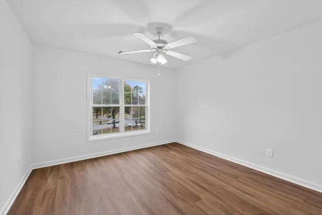 a view of an empty room with wooden floor and a window