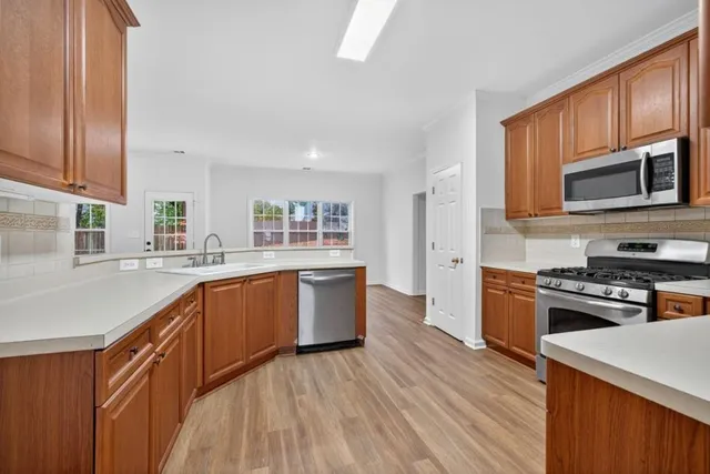 a kitchen with stainless steel appliances granite countertop wooden cabinets a stove top oven with wooden floor