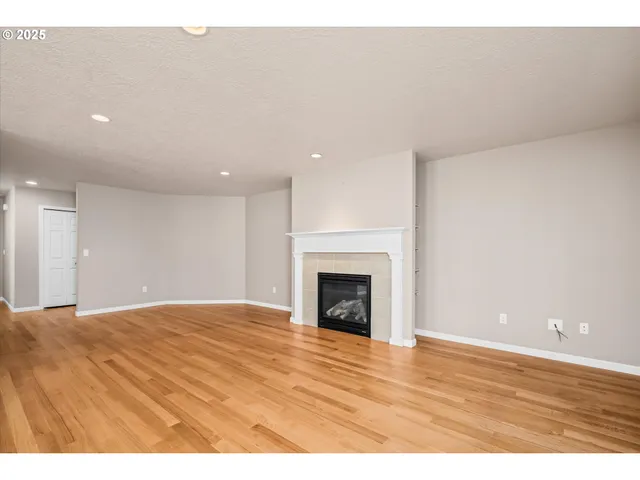 a view of empty room with wooden floor and fireplace