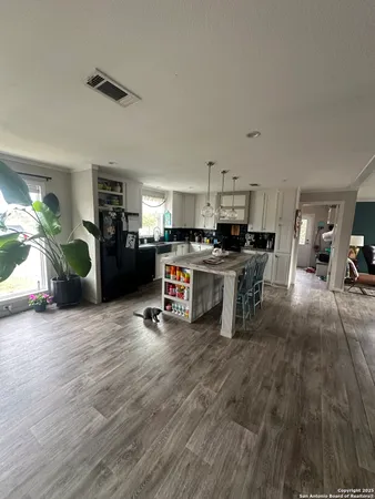 a kitchen with stainless steel appliances kitchen island granite countertop a stove a refrigerator a sink a dining table and chairs with wooden floor