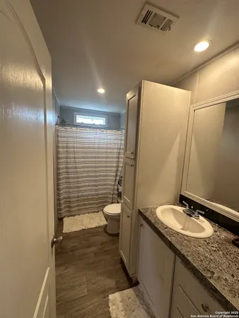 a bathroom with a granite countertop sink toilet and shower