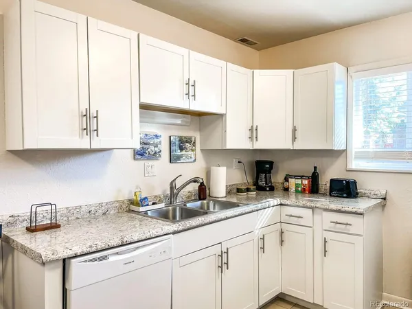 a kitchen with stainless steel appliances granite countertop white cabinets sink and a granite counter top