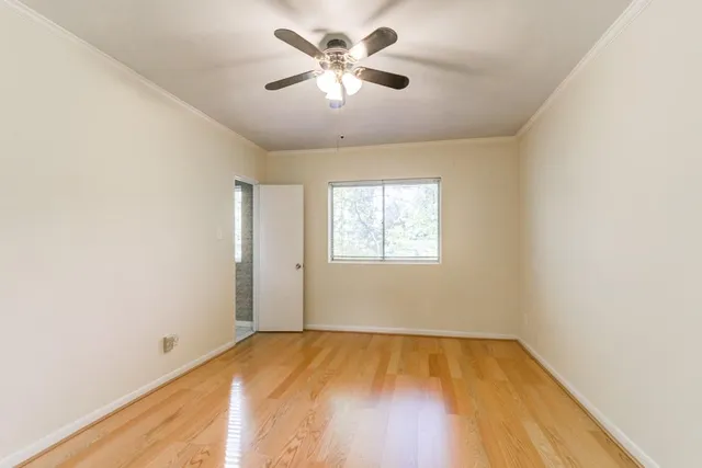 an empty room with a window and a ceiling fan