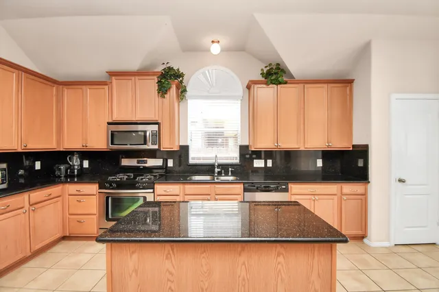 a kitchen with stainless steel appliances a sink a stove a microwave a sink and cabinets