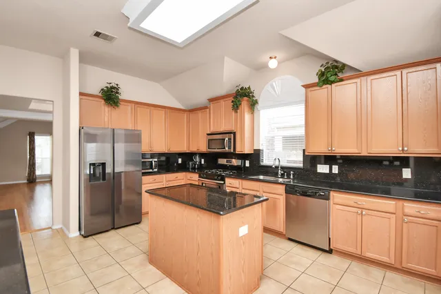 a kitchen with stainless steel appliances granite countertop a refrigerator a sink and white cabinets