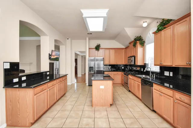 a large kitchen with granite countertop a large counter top cabinets and stainless steel appliances