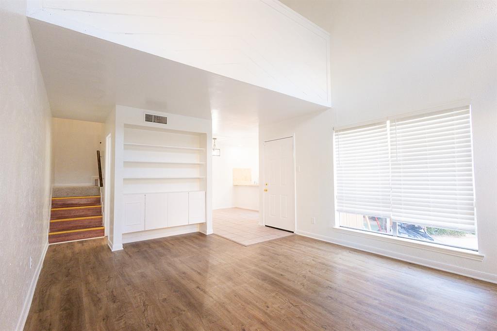 5540 Boca Raton Boulevard, Unit 175 Fort Worth, TX 76112 - Photo 12 of 30 Unfurnished living room with wood finished floors, stairs, built in shelves, and a high ceiling
