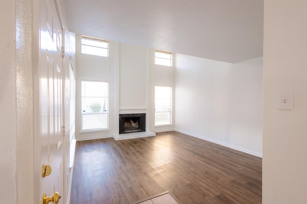 5540 Boca Raton Boulevard, Unit 175 Fort Worth, TX 76112 - Photo 2 of 30 Unfurnished living room with a fireplace with raised hearth and dark wood finished floors