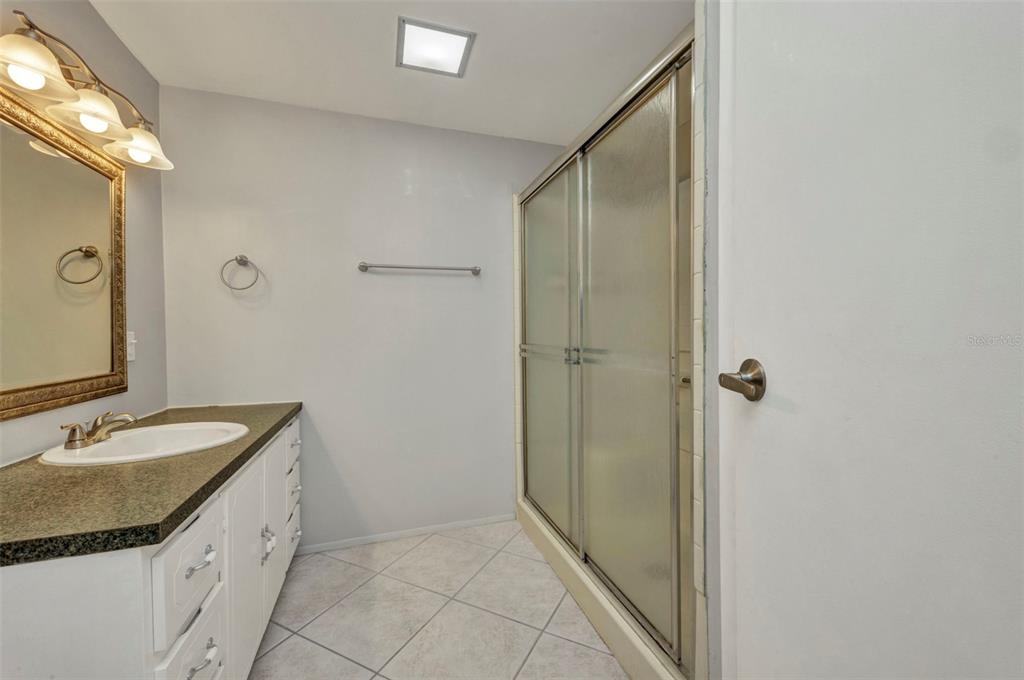 10100 Burnt Store Road, Unit 21 Punta Gorda, FL 33950 - Photo 28 of 61 a bathroom with a granite countertop sink a mirror and a shower