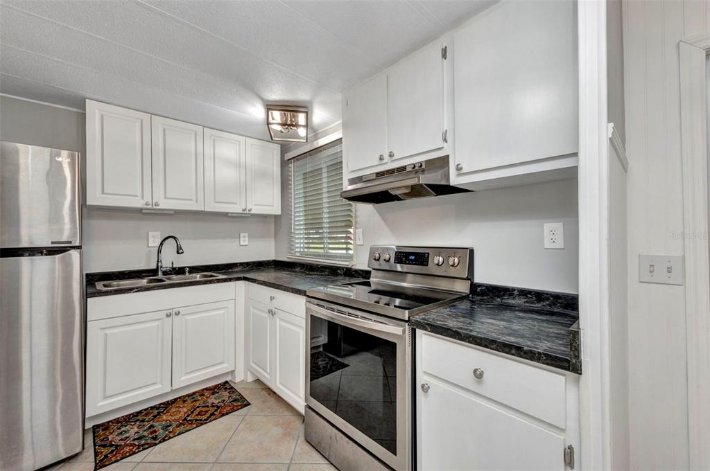10100 Burnt Store Road, Unit 21 Punta Gorda, FL 33950 - Photo 6 of 61 a kitchen with granite countertop stainless steel appliances and white cabinets