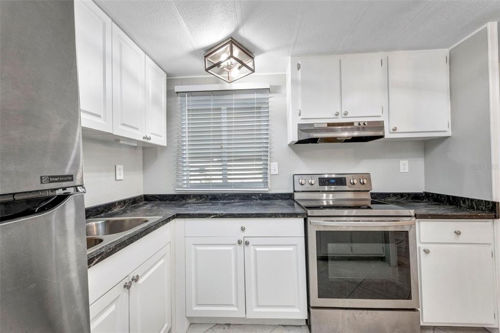 10100 Burnt Store Road, Unit 21 Punta Gorda, FL 33950 - Photo 9 of 61 a kitchen with stainless steel appliances granite countertop a sink a stove and cabinets