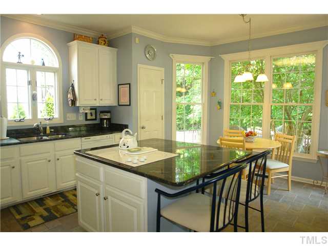 7012 Edgeview Court Raleigh, NC 27613 - Photo 11 of 25 a kitchen with a table chairs and wooden cabinets