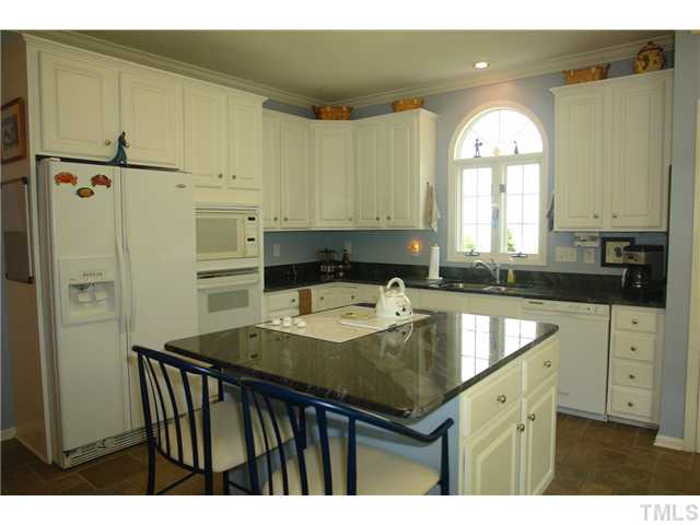7012 Edgeview Court Raleigh, NC 27613 - Photo 10 of 25 a kitchen with a sink a refrigerator and cabinets