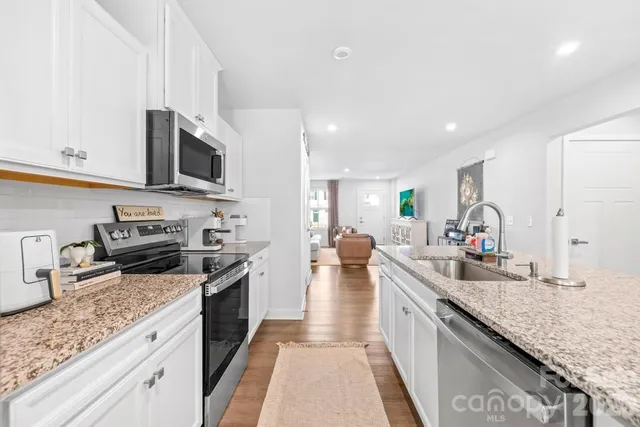 a large kitchen with a stove top oven a sink a counter space and cabinets