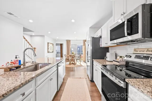 a large kitchen with stainless steel appliances granite countertop a lot of counter space and a sink