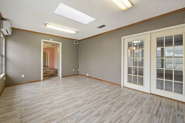 a view of an empty room with wooden floor and windows