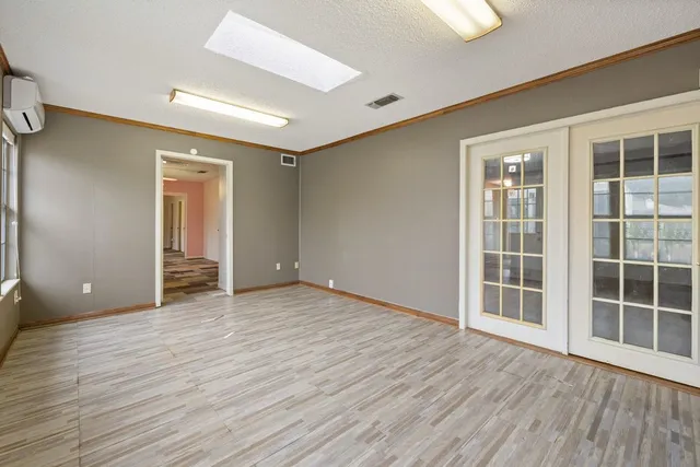 a view of an empty room with wooden floor and windows
