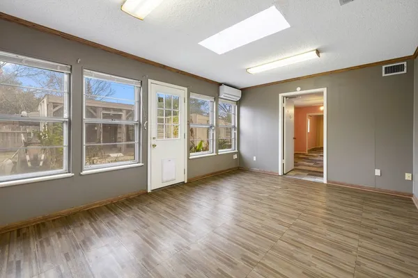 a view of an empty room with wooden floor and a window