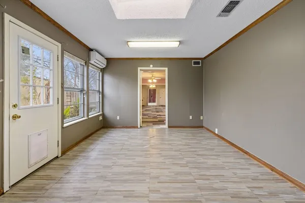 a view of an empty room with a window and wooden floor