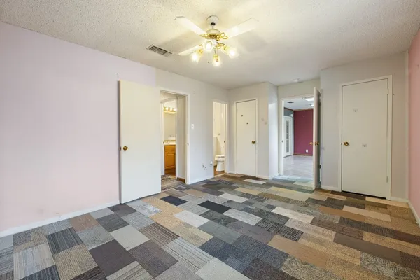 a view of a bedroom with a chandelier fan and a bathroom