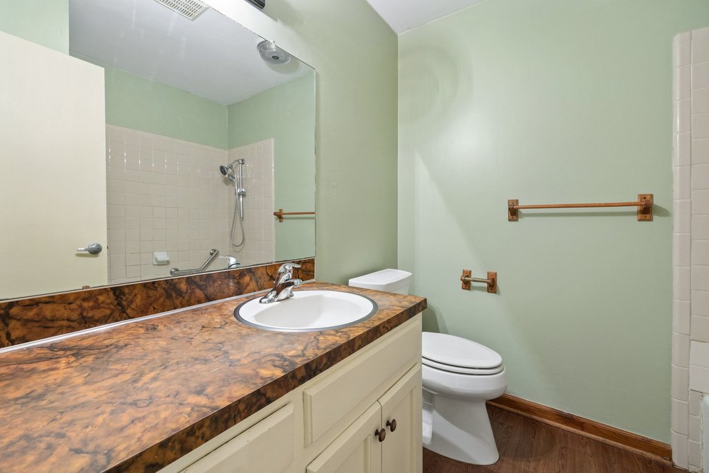 2204 Smith Avenue Taylor, TX 76574 - Photo 32 of 40 a bathroom with a granite countertop sink a toilet and a mirror