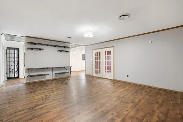 a view of an empty room with wooden floor and a window