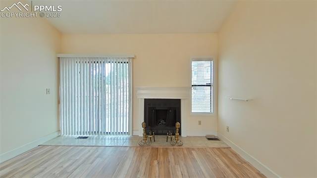 460 Autumn Ridge Circle, Unit D Colorado Springs, CO 80906 - Photo 27 of 38 Unfurnished living room with baseboards, visible vents, wood finished floors, and a fireplace